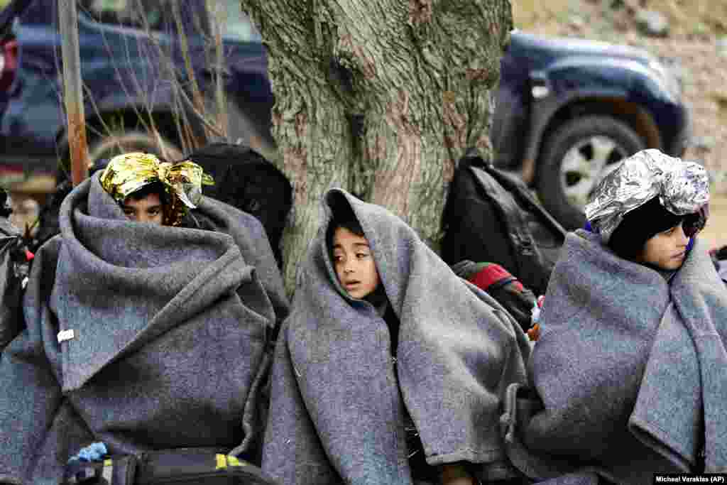 In the village of Skala Sikaminias, on the Greek island of Lesbos, children from Afghanistan use blankets to warm themselves after crossing the Aegean Sea from Turkey. (AP/Michael Varaklas)