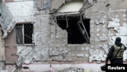 Un procuror ucrainean pentru crime de război inspectează o clădire avariată de un atac militar rusesc în Herson, la începutul acestei luni. 