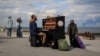 A street musician gives an impromptu concert on the beach as smoke rises over the port of Pivdenniy after Russian missiles in Odesa on April 19.
