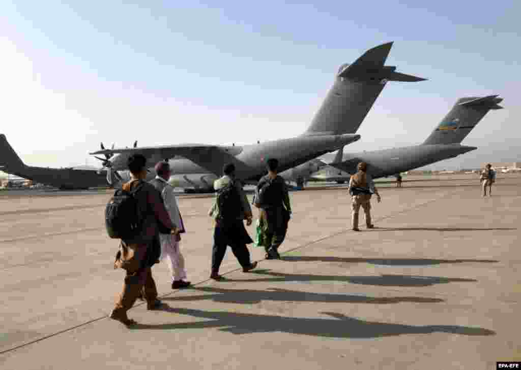 People line up to board a military aircraft as they are evacuated from Kabul airport on August 23.