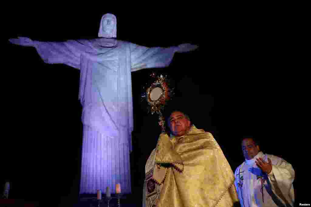 Uskrsni događaj u nedjelju kod kipa Krista Otkupitelja, u Rio de Janeiru - Nadbiskup Doma Rio O Janeiro u Rio de Janeiru drži križ nad kipom Krista Otkupitelja tokom uskrsnih nedjelja usred epidemije korona virusa (COVID-19), u Rio de Janeiru, Brazil, 12. aprila 2020.&nbsp;