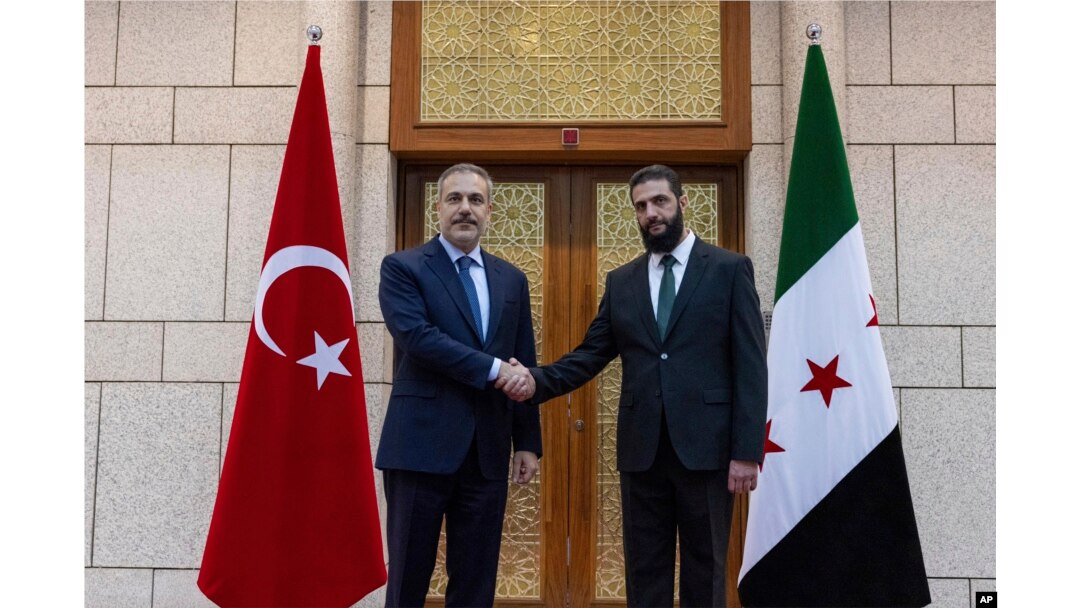 Ministrul turc de externe, Hakan Fidan (stânga), dă mâna cu Ahmad al-Sharaa (dreapta), cunoscut anterior sub numele de luptă Abu Mohammed al-Golani, în timpul întâlnirii lor de la Damasc, Siria, 22 decembrie 2024.