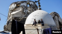 Copii palestinieni pe ruinile unei moschei distrusă în cei doi ani de război din Gaza. (11 februarie 2026)