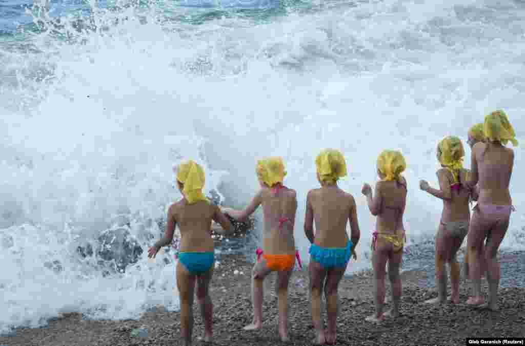 Children play at a beach in the rain near the Crimean village of Berehove on the Black Sea. (Reuters/Gleb Garanich)