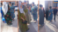 An official from the Committee for Women's Affairs in the Rudaki district speaks to women on the streets as part of a campaign to promote Tajik national clothing. (composite photo)