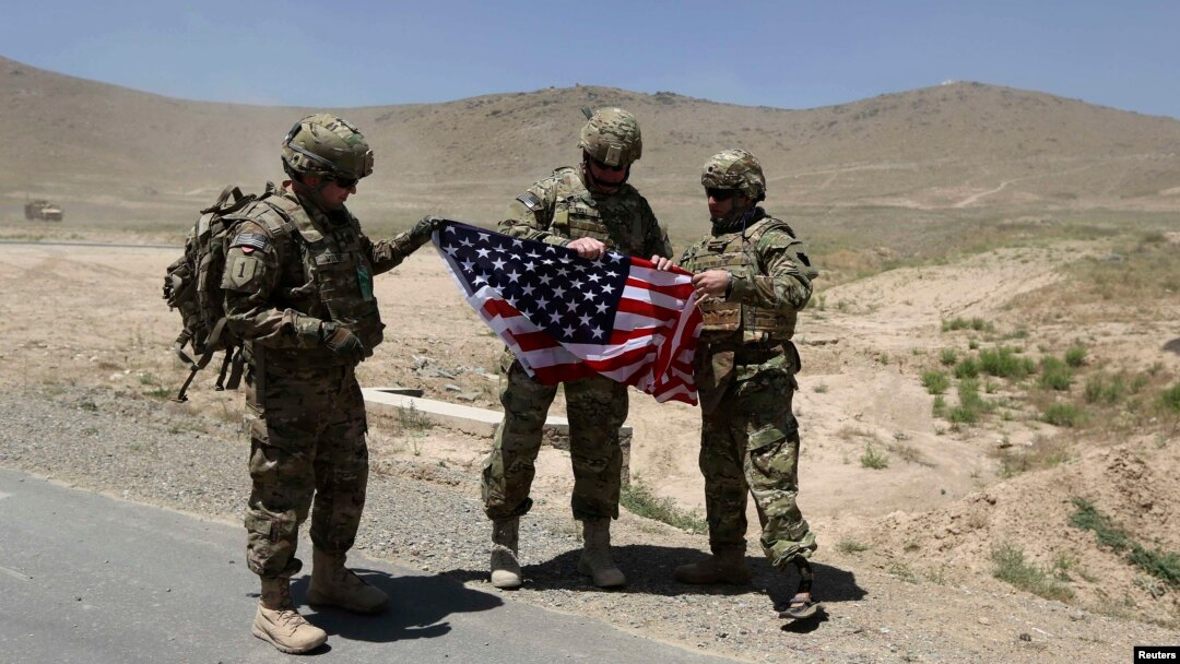 NATO soldiers stand with a U.S. flag after a security handover ceremony at a military academy outside Kabul in June.