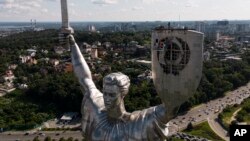 Workers remove the symbol from the Motherland monument in Kyiv on August 1.