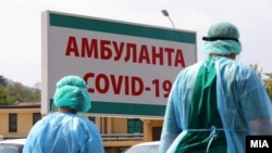 Dy punonjës shëndetësorë qëndrojnë pranë Klinikës Infektive në Shkup. 