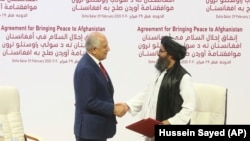 ABŞ-nyň Owganystanda parahatçylygy gazanmak boýunça ýörite wekili Zalmaý Halilzad (ç) we "Talybanyň" syýasy baştutany Molla Abdul Ghani Baradar (s), Doha, 29-njy fewral 2020