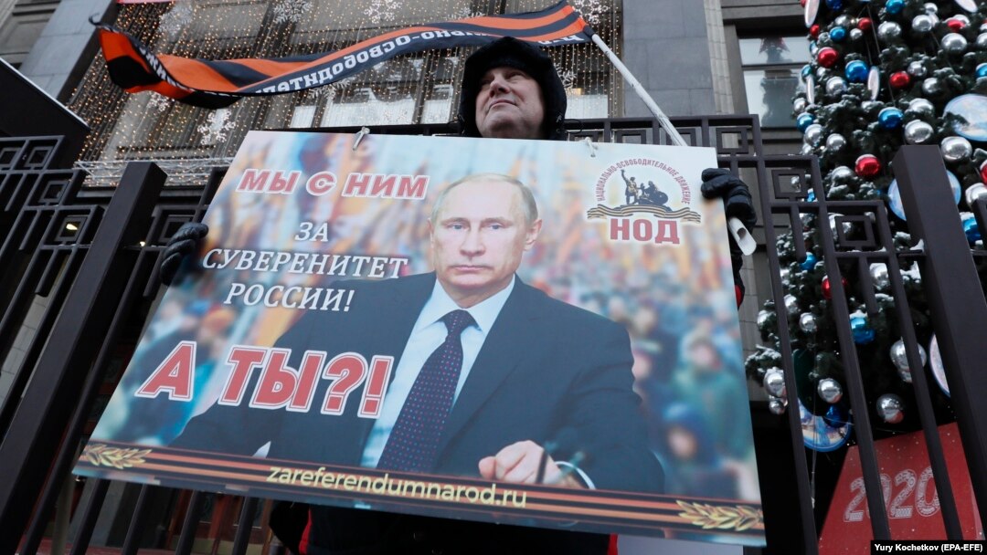 An activist from a pro-Kremlin movement holds a placard with a portrait of Russian President Vladimir Putin in front of the State Duma in Moscow on January 23.