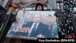 An activist from a pro-Kremlin movement holds a placard with a portrait of Russian President Vladimir Putin in front of the State Duma in Moscow on January 23.