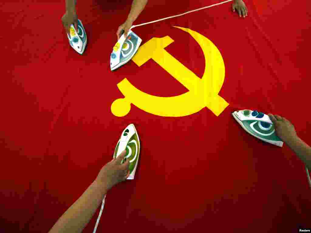 To mark the 90th anniversary of China's Communist Party, workers use irons to smooth out a Communist Party of China flag at a Beijing flag factory.Photo by David Gray for Reuters