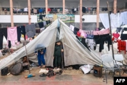 Palestinian boys stand in their makeshift tent at a camp set up in a schoolyard in Rafah in the southern Gaza Strip on December 13, 2023.