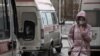 A woman wearing a protective face mask walks past ambulances outside a hospital in Omsk. 