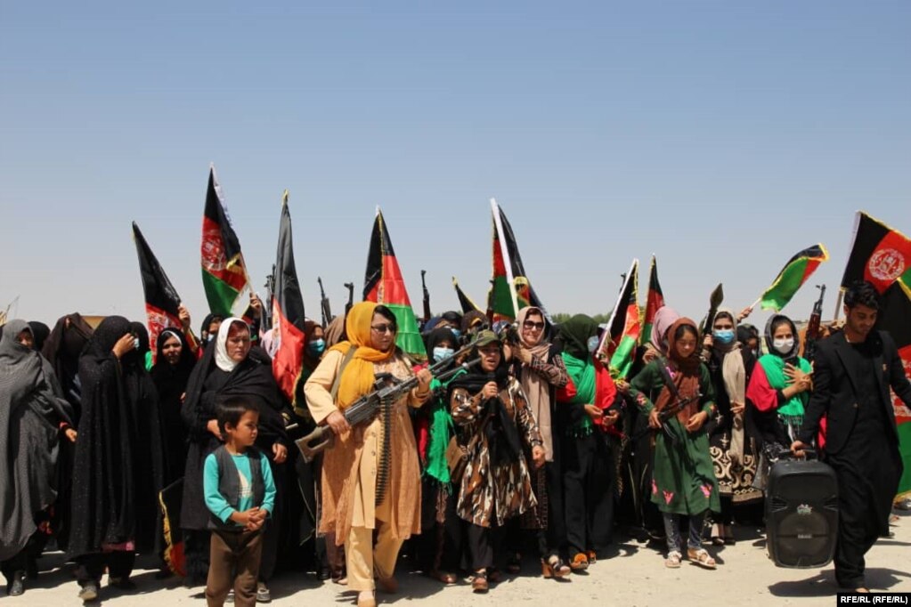 Gratë mbajnë armë automatike derisa marshojnë kundër talibanëve në provincën Ghor, më 6 korrik.
