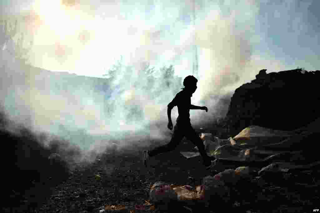 A Kurdish man runs away from tear gas thrown by police in the Turkish village of Mursitpinar next to the Syrian town of Ain al-Arab, known as Kobani by the Kurds, on the Turkish-Syrian border. (AFP/Aris Messinis) 