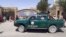Taliban militants drive a police vehicle as they gather around a provincial government office after taking control of Herat on August 13.