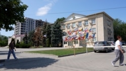 Moldova, People walk down the street with the Gagauzia People's Assembly building in the background, Comrat, July 29, 2026