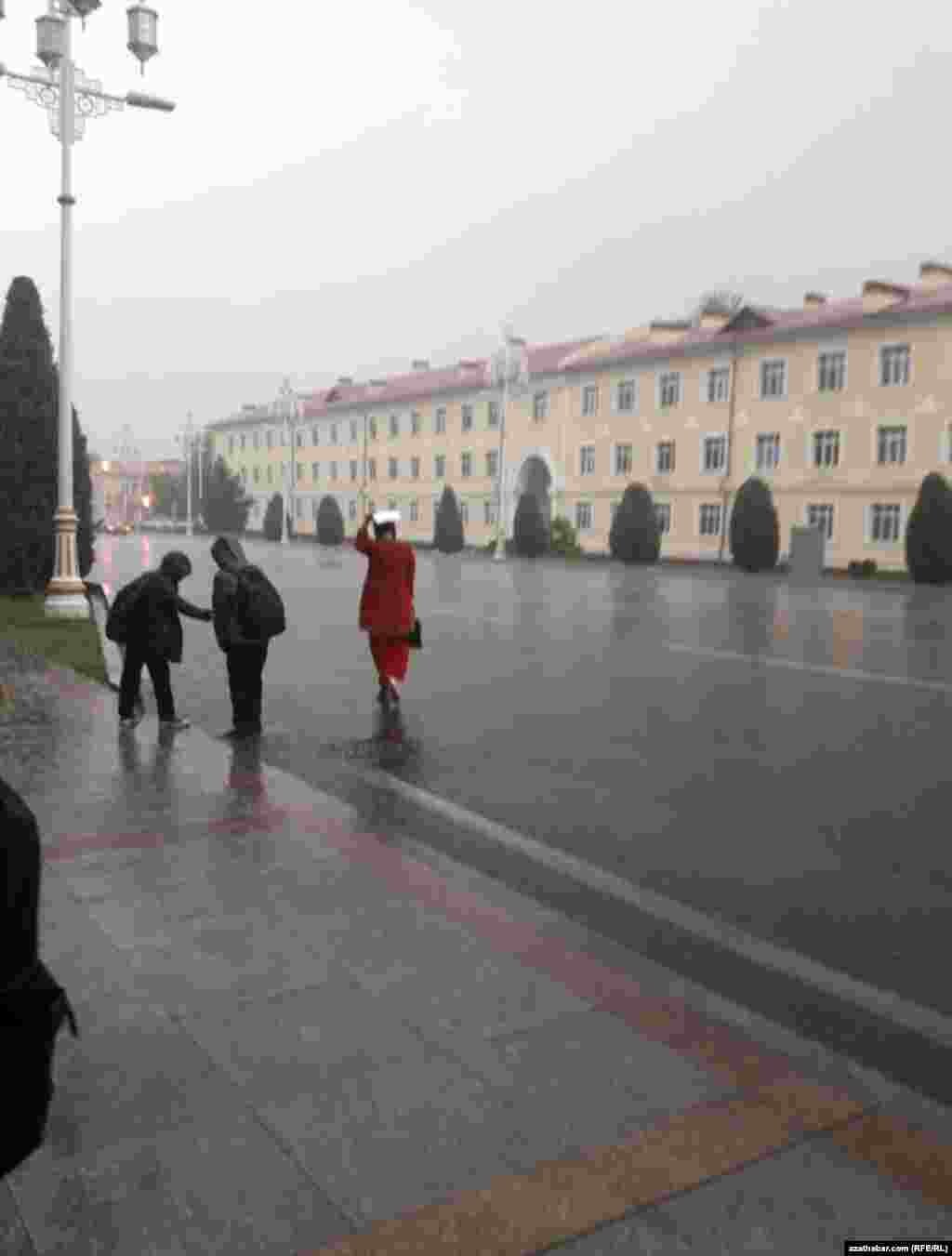 Aşgabat, boş köçe, ýagyşly howada taksi tutjak bolýan gyz. Aprel, 2020.