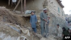 Pakistani residents gather next to the rubble of damaged house following an earthquake in Bajaur in October 2015.