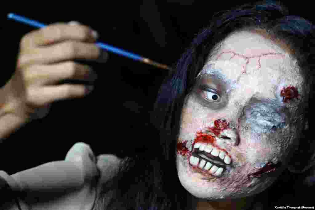 Це 32-річна мешканка Бангкоку (Таїланд) Канітта Тонгнак. На фото вона завершує макіяж перед початком онлайн-трансляції. Канітта &ndash; інтернет-підприємець, в образі зомбі вона продає одяг померлих людей &nbsp;