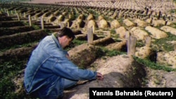 An unnamed man mourns his mother, Vasvija, who was killed by a sniper, at a cemetery built at the Kosevo stadium in Sarajevo, September 1993.
