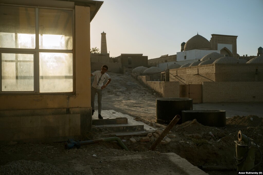 A man peers from the entrance to a building in Khiva next to where major earthworks are under way.