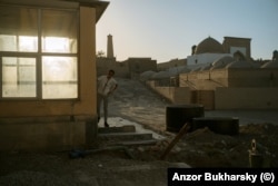 A man peers from the entrance to a building in Khiva next to where major earthworks are under way.