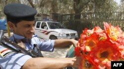 A police officer in Baghdad affixes plastic flowers to the front of a police car as the nation prepares for the official withdrawal of U.S. troops from cities and towns.