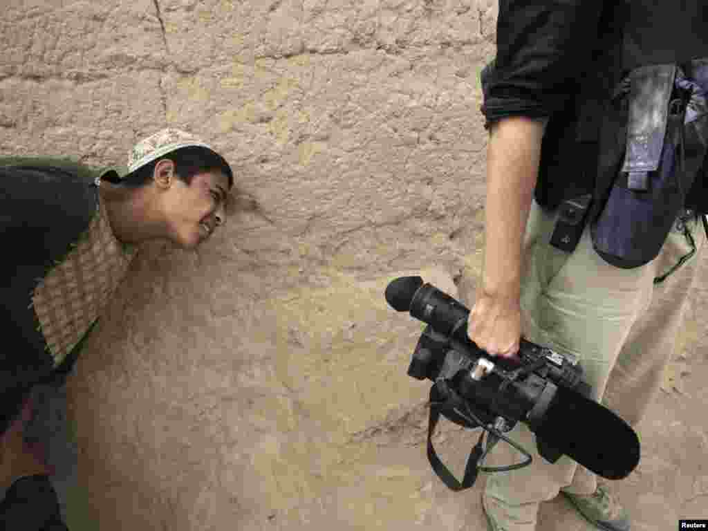 An Afghan boy tries to get a peek through the viewfinder of a journalist's video camera in the village of Saidon Kalacheh, north of Kandahar, on July 28. Photo by Bob Strong for Reuters