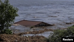 Acoperișul unei case plutește pe râul Nipru, după ce a fost luat de inundațiile provocate de spargerea barajului Nova Kakhovka din Ucraina pe 6 iunie.