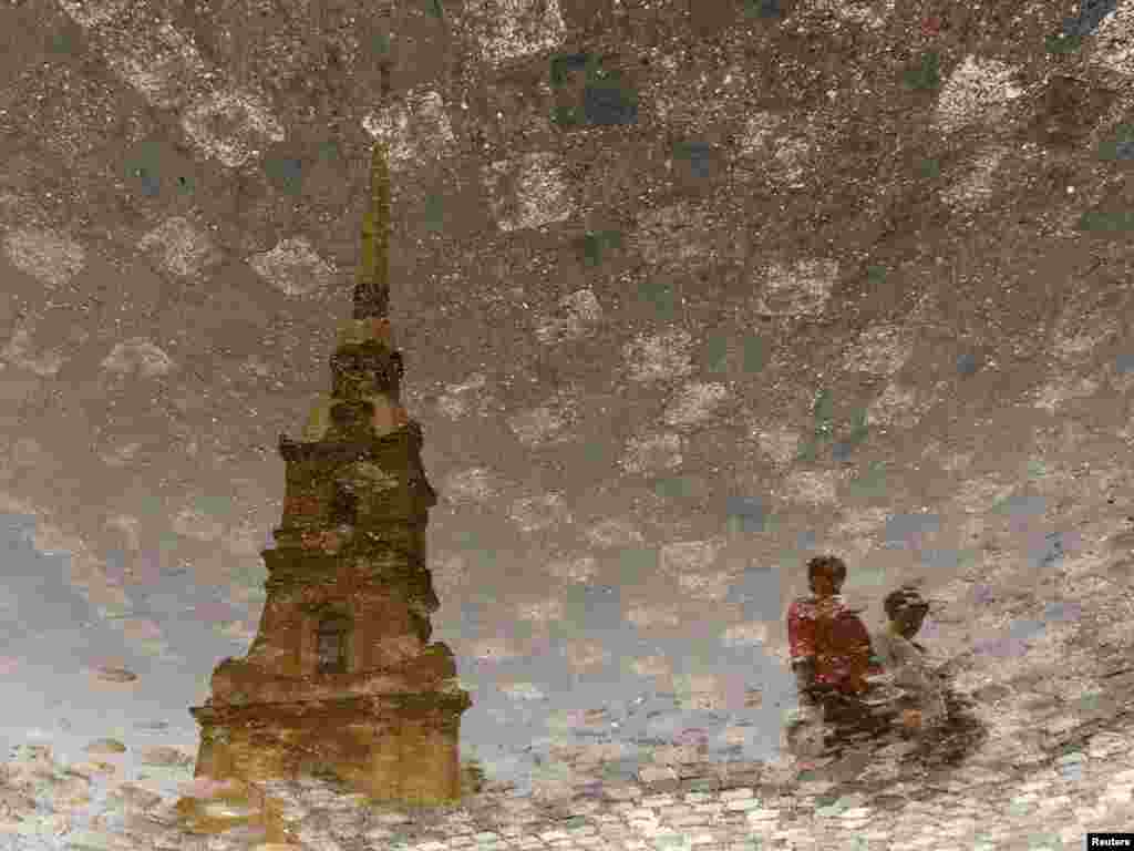 Tourists are reflected in a puddle, with the Peter and Paul Fortress seen nearby, in St. Petersburg, Russia. Thousands of tourists visit the popular site, which was a city garrison and a prison for high-ranking or political inmates. It also became the last refuge for Russian tsars.Photo by Alexander Demianchuk for Reuters