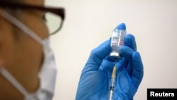 Медицинский персонал готовит вакцину против коронавируса Moderna (COVID-19) для введения в недавно открывшемся центре массовой вакцинации в Токио, Япония, 24 мая 2021 года. 