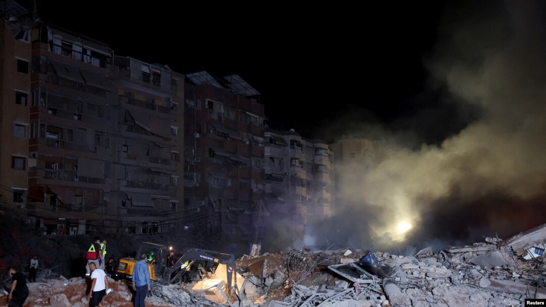 Oamenii inspectează rămășițele de pe urma loviturii israeliene de vineri seară asupra Beirutului care au pus la pământ șase blocuri de locuințe.