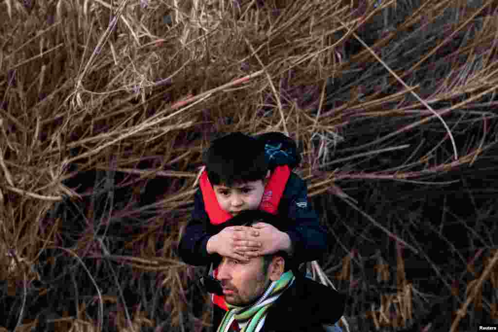 An Afghan man carries his son after arriving on the island of Lesbos.&nbsp;Under a 2016 agreement with the European Union, Turkey had restricted migration flows from Syria and other countries to Europe.&nbsp;