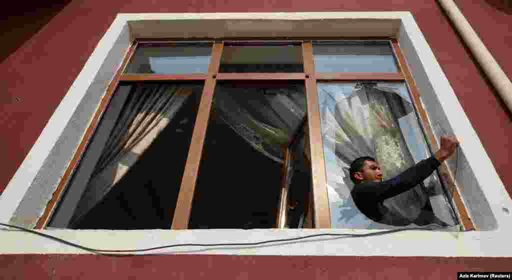 A man removes glass from a window that was allegedly damaged by recent shelling during the fighting over the breakaway region of Nagorno-Karabakh in the city of Tartar, Azerbaijan. (Reuters/Aziz Karimov)