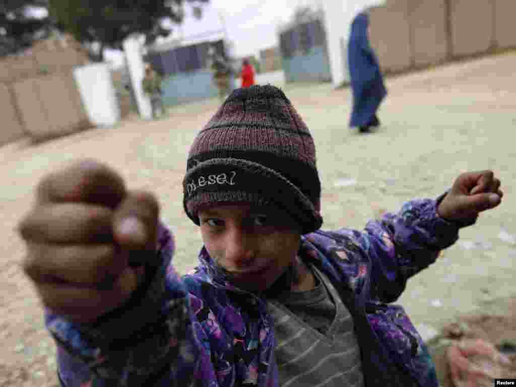 An Afghan boy gestures in front of an international combat outpost in Iman Sahib, Afghanistan. Photo by Fabrizio Bensch for Reuters