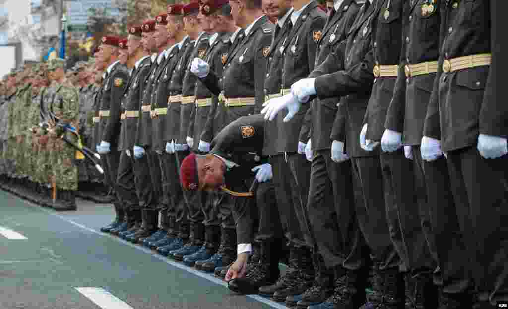 A Ukrainian soldier cleans his shoes as stands with his comrades in line on a central street in downtown Kyiv during rehearsals for a military parade that will be held in honor of Independence Day on August 24. (epa/Roman Pilipey)