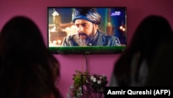 A family watches the Turkish drama series Dirilis: Ertugrul on Pakistani TV during the holy month of Ramadan in Islamabad.