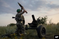 A Ukrainian soldier of the 3rd Assault Brigade fires a 122mm mortar toward Russian positions at the front line near Bakhmut.