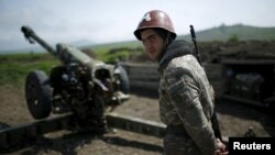 An ethnic Armenian soldier stands next to a cannon at artillery positions near Nagorno-Karabakh's town of Martuni. 