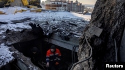 A resident on January 10 shows where a Russian drone struck the roof of an apartment building in the Ukrainian capital, Kyiv.