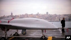 Војник на морнарицата стои до борбено беспилотно летало Bairaktar TB3 (UCAV) на турскиот амфибиски јуришен брод TCG Anadolu L400, во Истанбул (20 април 2023 година).