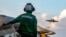 A US sailor observes flight operations during Operation Epic Fury. The US military is enforcing a blockade of the Strait of Hormuz to cut off ships from using Iranian ports. 