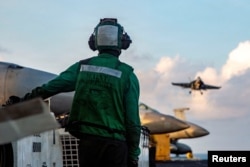 A US sailor observes flight operations during Operation Epic Fury. The US military is enforcing a blockade of the Strait of Hormuz to cut off ships from using Iranian ports.