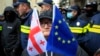 A woman with the EU and Georgian flags stands in front of police blocking a street during a an opposition rally in Tbilisi. (file photo)