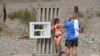 Turisti se slikaju ispred uređaja koji mjeri i pokazuje visinu temperature zraka u Dolini smrti, Kalifornija (17. juni 2021.)