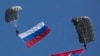 Serbian paratroopers descend to the ground holding Serbian and Russian (L) national flags during a training exercise in the village of Nikinci, west from Belgrade, November 14, 2014