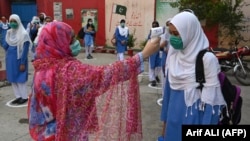 A teacher checks the body temperature of students at a government school in Lahore on September 15. 