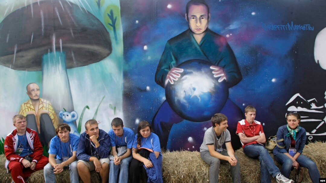Activists sit near graffiti depicting Russian President Vladimir Putin at the summer camp of the pro-Kremlin youth group Nashi at Lake Seliger this past summer.